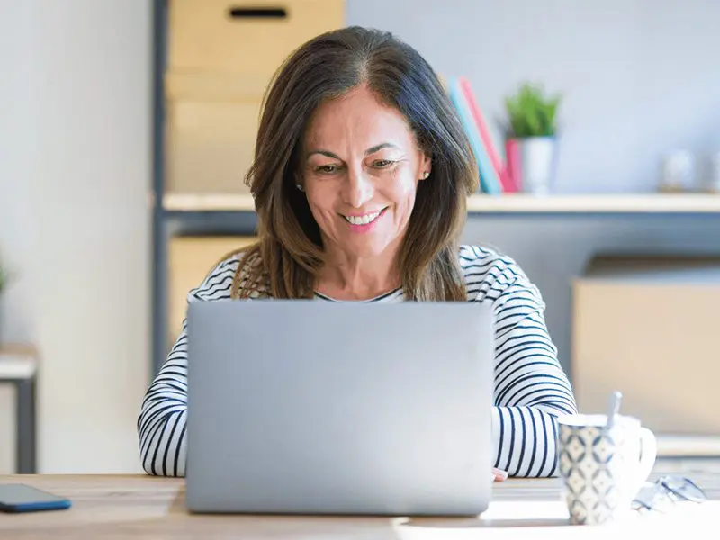 Smiling woman looking at her laptop.