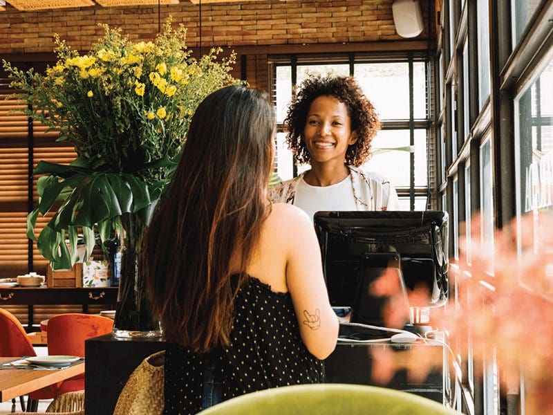 Two women sitting at a desk having a conversation.